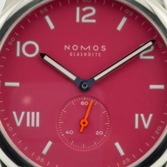 NOMOS watch with a red face and silver case