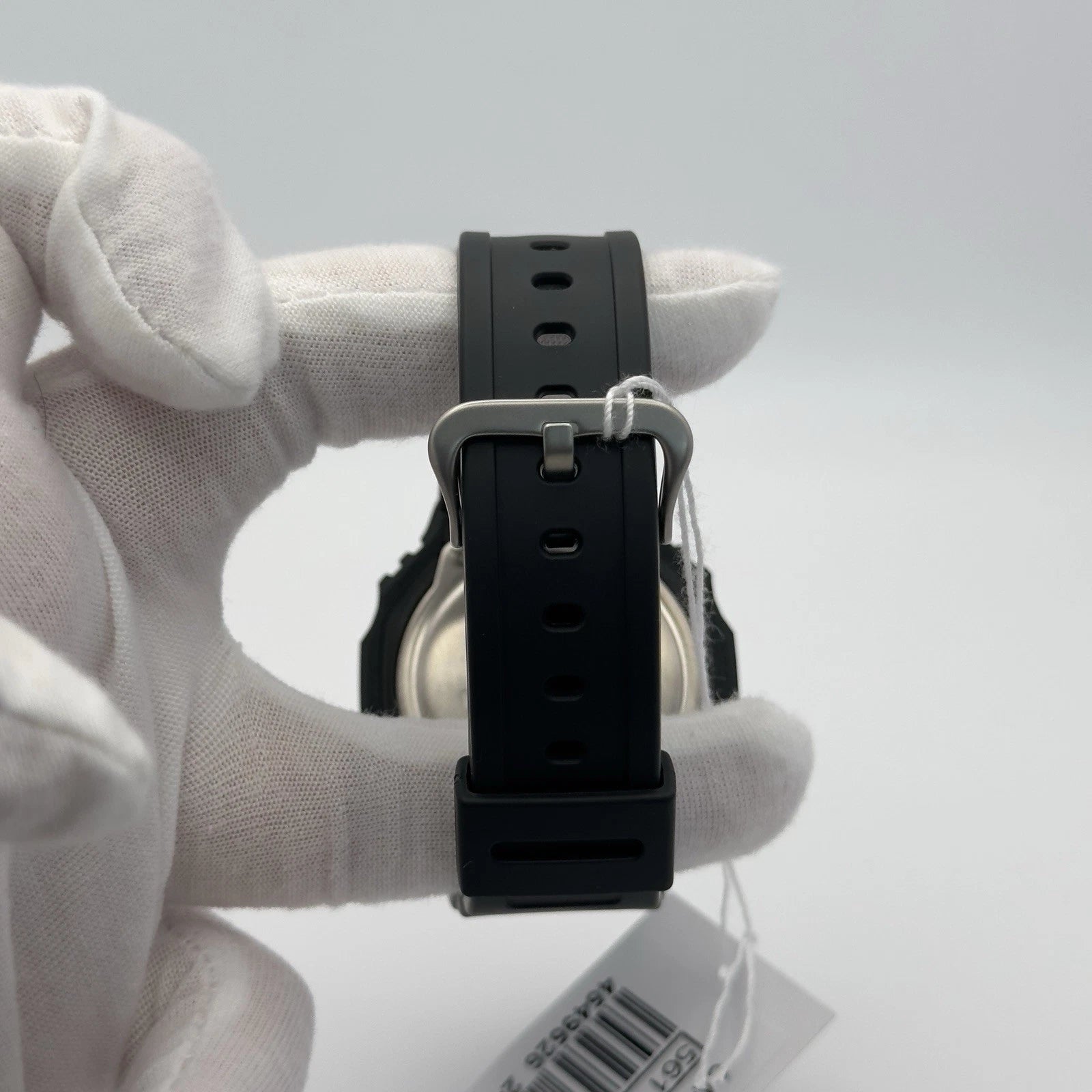 Black watch strap held by a gloved hand against a light gray background