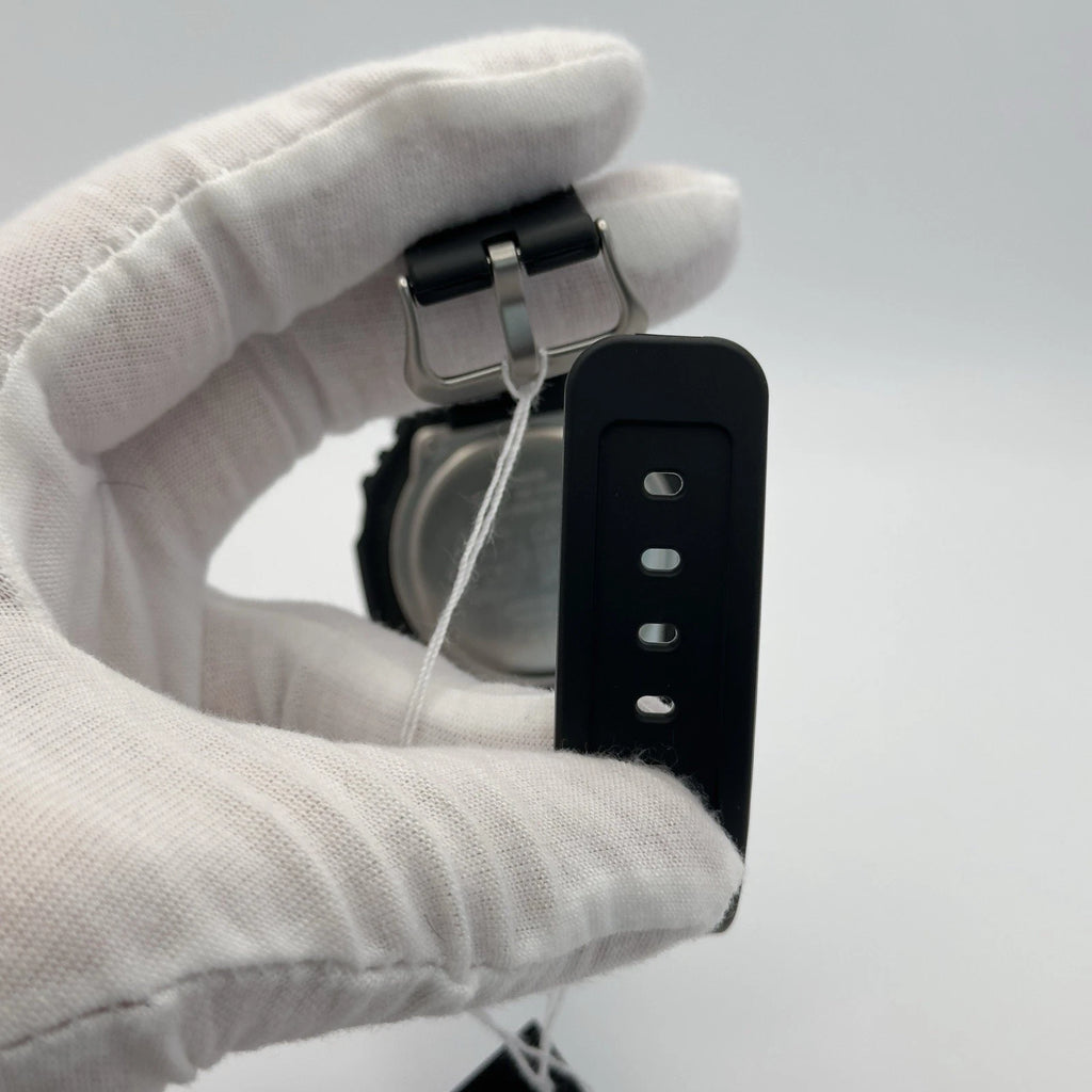 Black watch strap being adjusted by a gloved hand on a light gray background