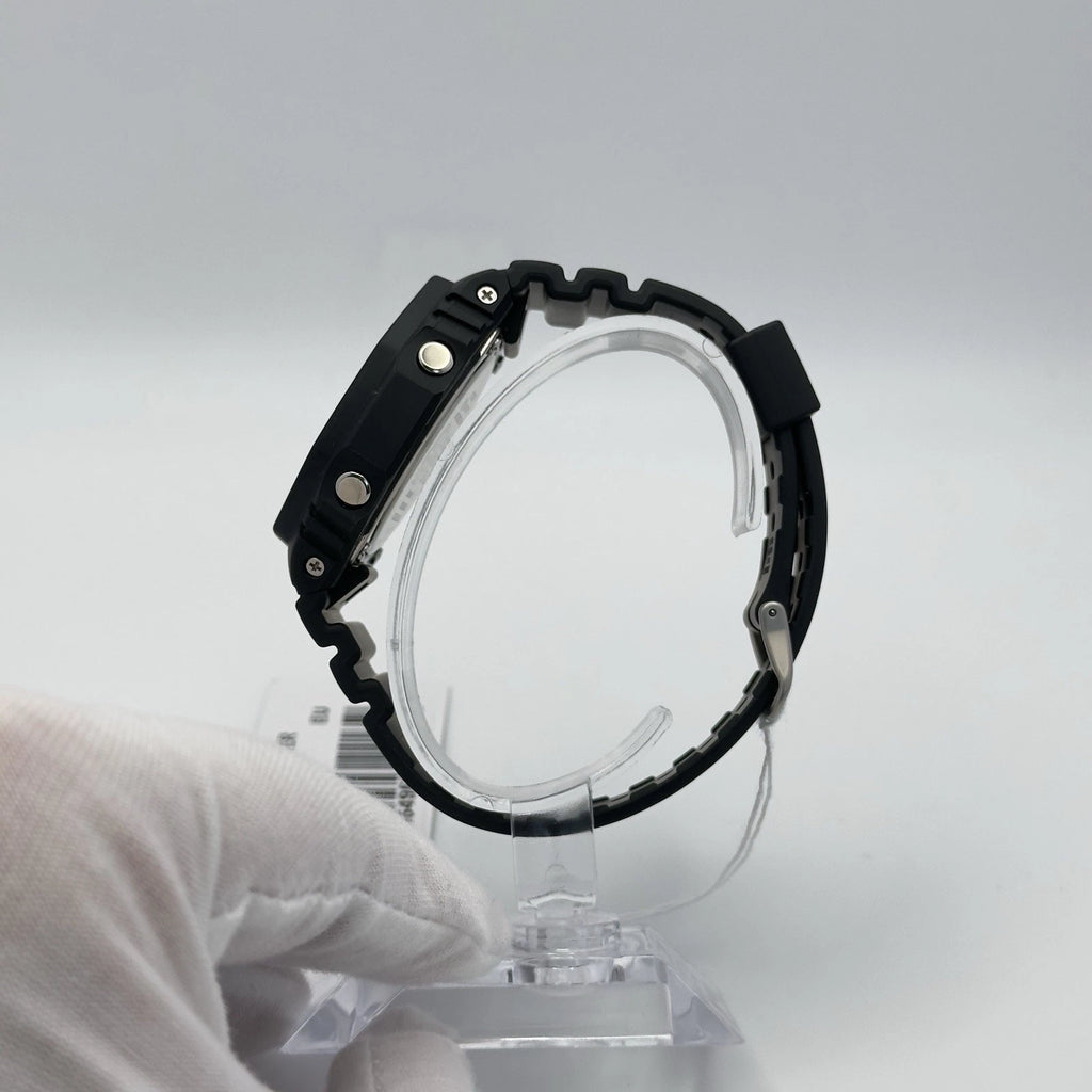 Black wristwatch on a clear stand against a gray background