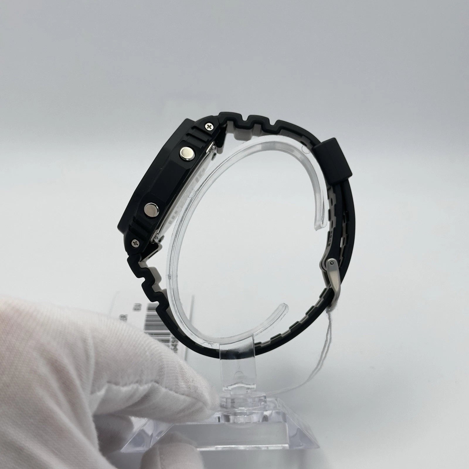 Black wristwatch on a clear stand against a gray background