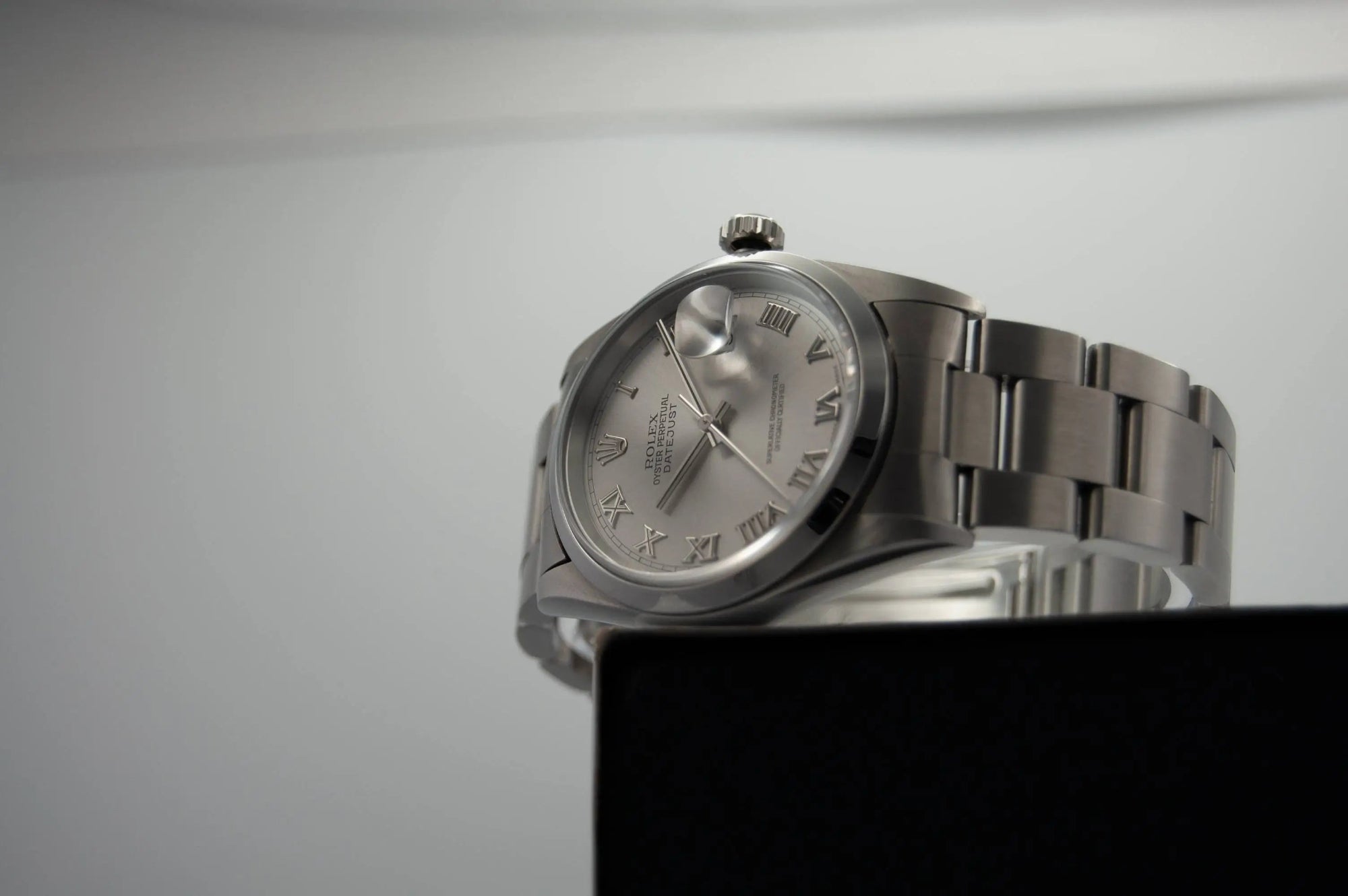 Silver wristwatch on a stand with a neutral background