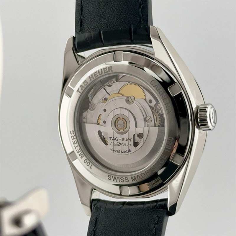 Back view of a Tag Heuer watch with visible mechanical components on a gray background
